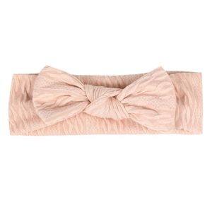Vue détaillée d'un bandeau rose tricoté pour bébé avec un grand nœud et une texture torsadée
