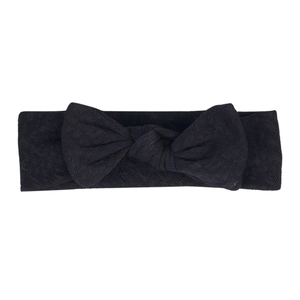 Detail of a deep black elastic baby headband with textured fabric and a large bow design
