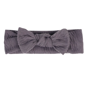 Gros plan d'un bandeau élastique violet foncé en tissu crépon doux avec un nœud papillon
