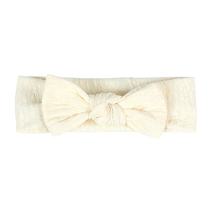 Close-up of cream knit baby headband featuring a large bow and soft textured fabric