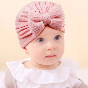 Detailed macro view of soft pink ribbed knit texture and large bow on baby turban hat