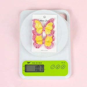 Detail view of pink and yellow glitter butterfly hair clips set on a display card