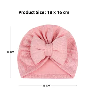 Pink ribbed knit baby turban hat with a large bow showing dimensions 18 x 16 CM