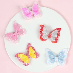 Detail of five colorful double-layered glitter butterfly hair clips on a ceramic plate