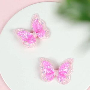 Macro detail of two pink glitter double-layered butterfly hair clips for girls