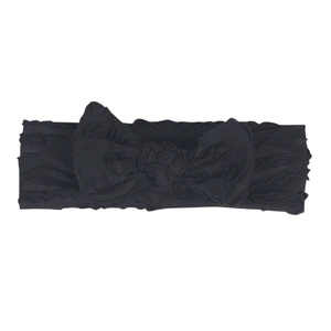 Close-up of black elastic newborn headband featuring a large bow and wavy ruffled edges