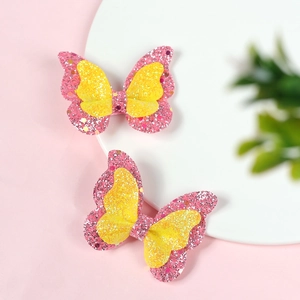 Detail of pink and yellow glitter butterfly hair clips on a soft white round pedestal