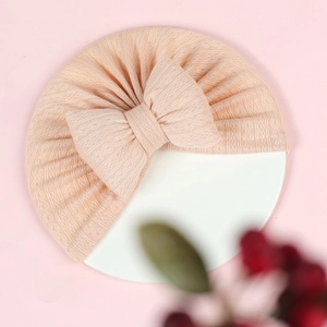 Close-up of ribbed apricot pink baby turban hat with a large padded decorative bow