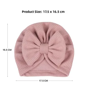 Pink ribbed baby beanie with a large bow detail measuring 17.5cm by 16.5cm