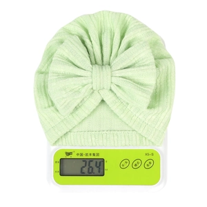 Macro shot of 26.4g light green ribbed baby turban hat with bow on digital scale