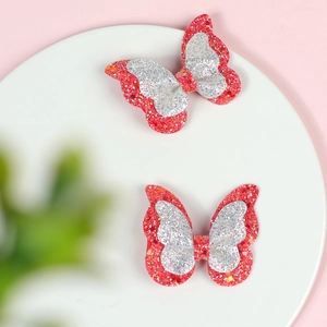 Detail of red and silver glitter double-layer butterfly hair clips on a white display