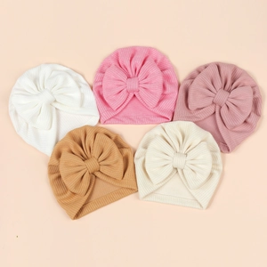 Ribbed knit baby hats with oversized bows in five Morandi colors arranged in a V-shape
