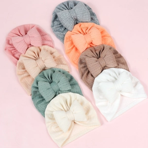 Flat lay of 8 colorful ribbed knit baby bow turbans in pink, grey, and neutral tones