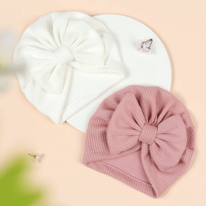 Close-up of ribbed knit baby turbans with large bows in white and dusty pink colors
