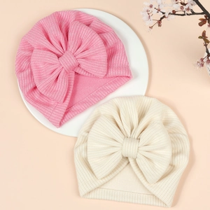 Two-pack of ribbed knit baby turban hats with large bows in soft pink and beige colors