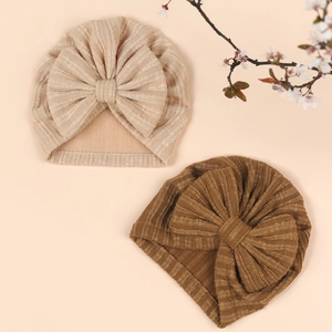 Close-up of soft ribbed baby turban hats in beige and brown with large bow details