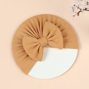 Detail of ginger yellow ribbed knit baby turban hat with a large bow on display