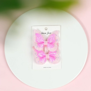 Detail of pink glitter double-layered butterfly hair clips on a white display card