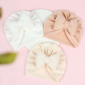 Detailed texture of baby waffle knit bow hats in white, pink and apricot colors