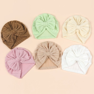 Flat lay macro of six pastel ribbed baby turbans with large bows in varied soft colors