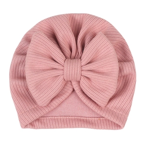 Detail of baby turban hat featuring a large bow and ribbed knit texture in dusty rose