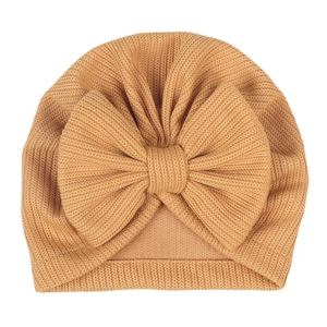 Detail of baby turban hat with large bow in caramel color and soft ribbed knit texture