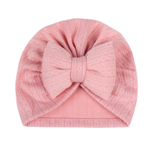 Close-up of pink ribbed baby hat featuring a large oversized stuffed cotton bow detail