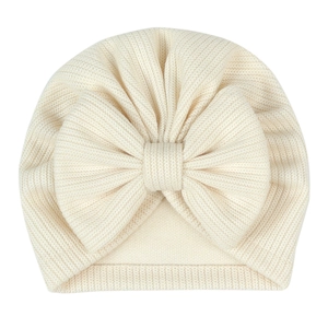 Macro detail of cream baby headband featuring a large knitted bow and fine ribbed texture