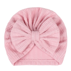 Pink ribbed knit baby turban hat with a large bow detail for girls on white background