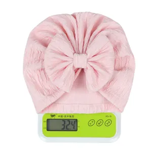 Pink infant turban hat with oversized bow on a scale showing lightweight 32.4g weight