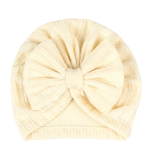 Detailed view of beige ribbed knit baby turban hat with a large decorative bow