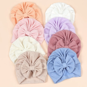 Flat lay of eight baby bow turbans in assorted pastel colors and ribbed knit fabric