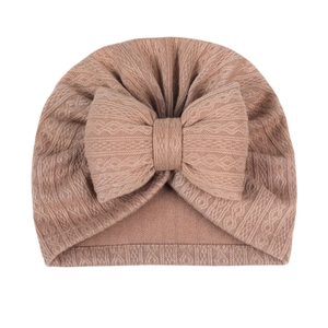 Detailed close-up of a knitted baby turban hat with a large bow in vintage brown fabric