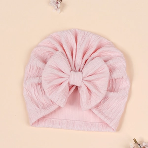 Detailed close-up of soft pink baby turban hat with oversized jacquard bow design