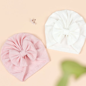Detail of pink and white baby turban hats with large bows and soft jacquard texture