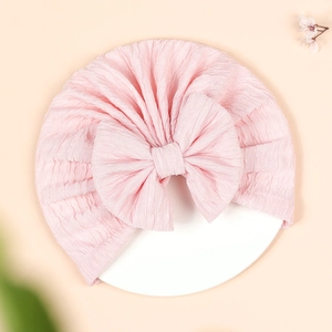Close-up detail of soft pink pleated baby turban hat with a large decorative bow