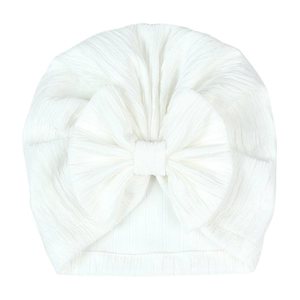 Detailed close-up of a white baby turban hat with a large bow and jacquard texture