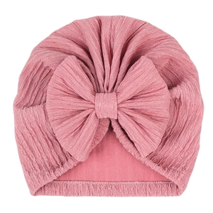 Detailed view of dark pink baby turban hat featuring a large bow and pleated knit texture