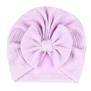 Detailed texture of light purple knitted baby turban hat with a large decorative bow
