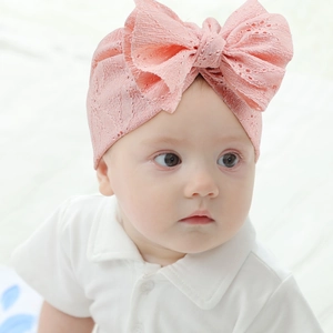 Gros plan du bonnet de bébé en dentelle rose avec texture évidée et grand nœud doux