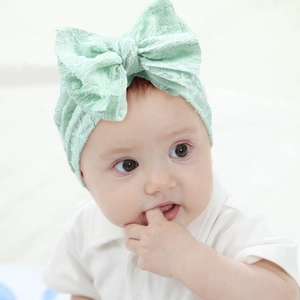 Detailed close-up of mint green baby headband with large knit bow and soft texture