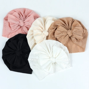 Vue à plat de bonnets de bébé en dentelle avec nœuds en cinq couleurs et maille ajourée