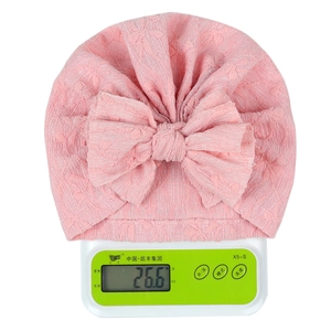 Close-up of pink infant turban hat with large bow weighing 26.6g on a digital scale