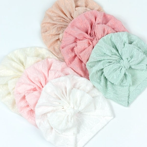 Flat lay of six baby turban hats with large bows in various soft pastel colors
