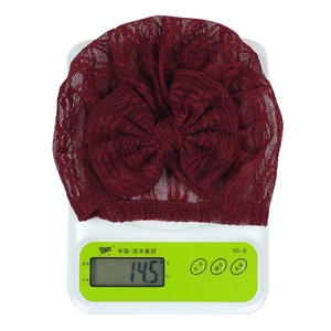 Detailed view of dark red newborn lace beanie with a large bow showing light weight of 14.5g