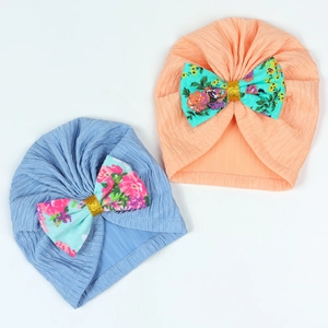 Detail of ribbed knit baby turbans with floral bow and gold sequin accents in two colors