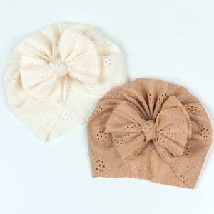 Détail de bonnets turban pour bébé en tricot ajouré beige et marron clair avec grands nœuds
