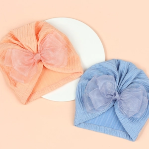 Detail of baby turbans with large organza bows in orange and blue soft knit fabric