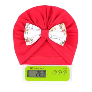 Détail du bonnet turban rouge pour bébé avec nœud floral pesant 26,3g sur balance