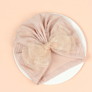 Detailed view of the baby turban's knit texture and its large organza bow decoration